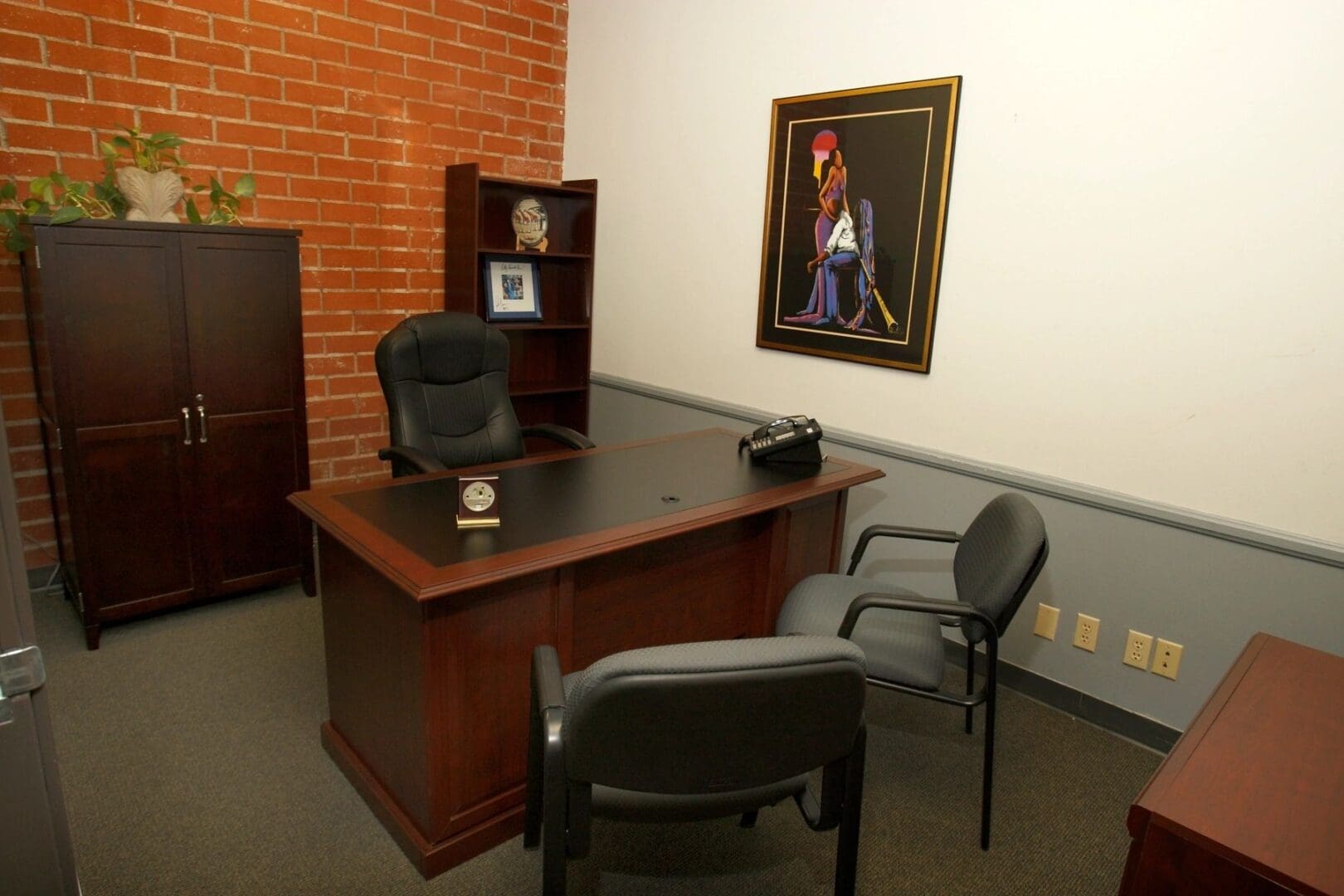 A room with chairs, desk and picture on the wall.
