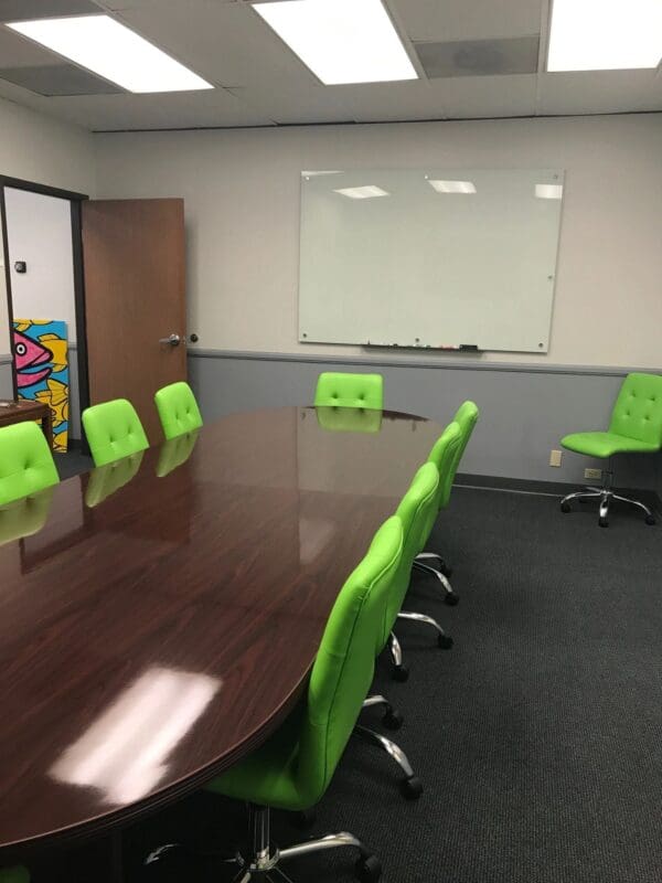 A conference room with green chairs and brown table.