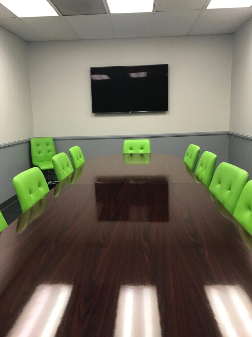 A conference room with green chairs and a large table.