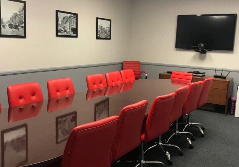 A conference room with red chairs and a large table.